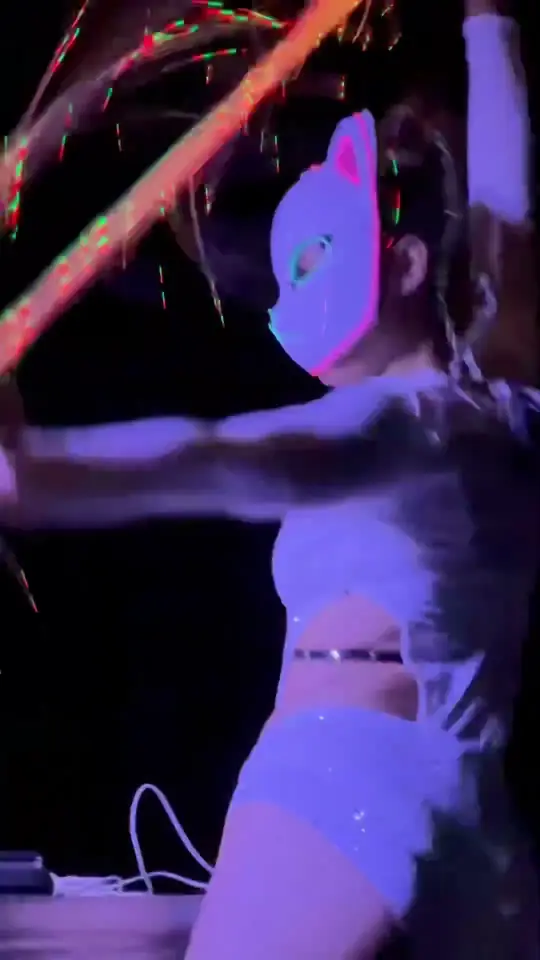 Play clip: a dancer in a white cat mask under violet light.
